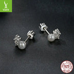 Prong-set sterling silver moissanite pearl earrings on dark textured surface