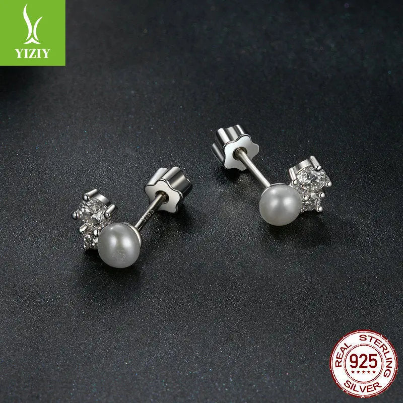 Prong-set sterling silver moissanite pearl earrings on dark textured surface