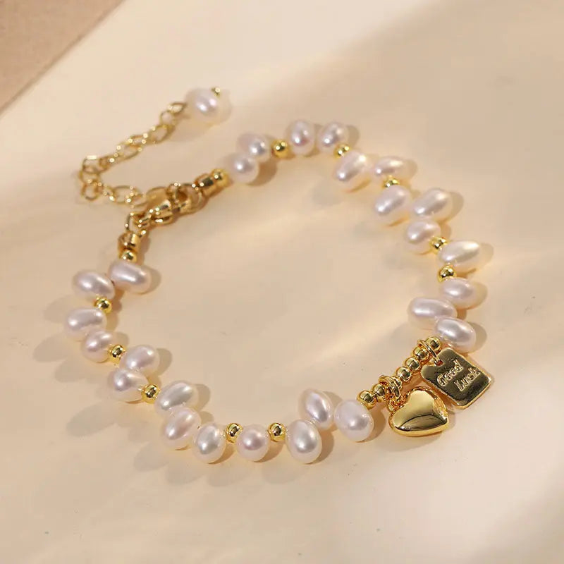 Natural freshwater pearl heart charm bracelet on a neutral beige background