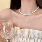 Dainty pearl choker necklace with a polished silver-toned bow charm