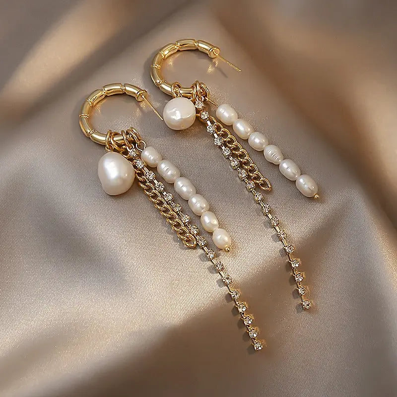 Gold bamboo hoop earrings with cascading freshwater pearls and rhinestone dangles on satin background