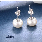 White freshwater pearl stud earrings with butterfly backings against a navy blue glitter background