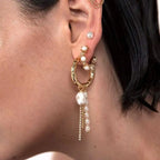 Model wearing gold bamboo textured statement hoop earring with dangling pearls and crystal fringe