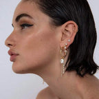 Asymmetrical gold bamboo hoop earring and pearl studs shown on model's ear
