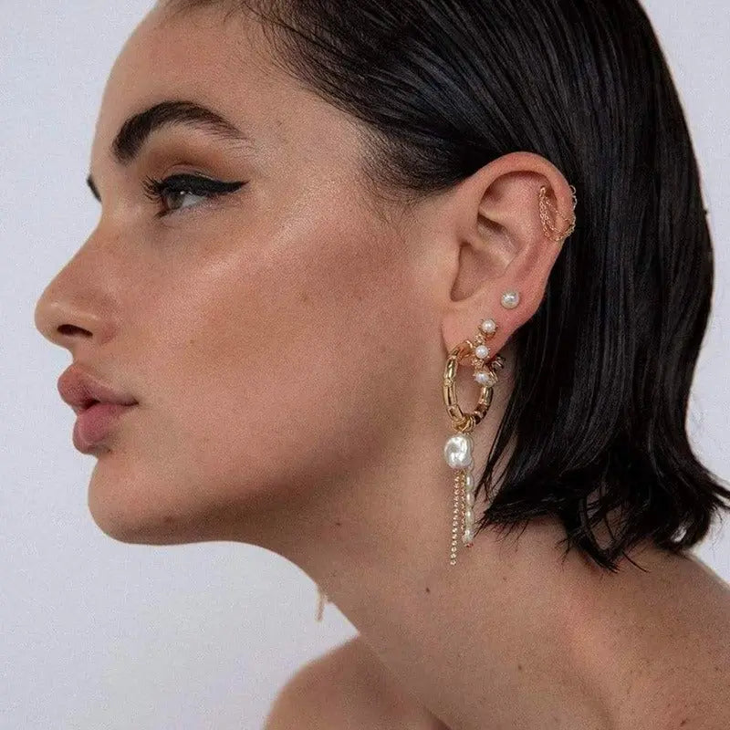 Asymmetrical gold bamboo hoop earring and pearl studs shown on model's ear