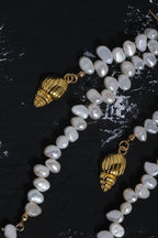Baroque Freshwater Pearl Conch Necklace and gold shell charms on dark marble background