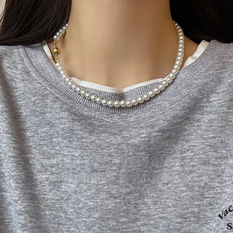 White pearl choker necklace with a spherical gold clasp on model