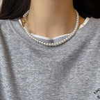 White pearl choker necklace with a spherical gold clasp on model