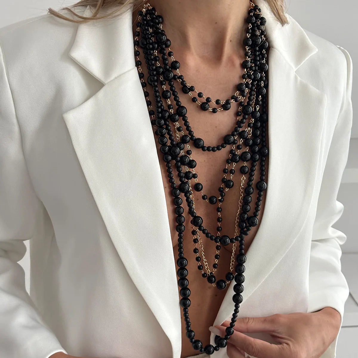 Pearl Layered Statement Body Chain in black beads and gold chains worn over a white blazer