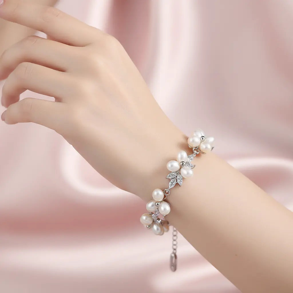 Luxury floral pearl bracelet on wrist with a background of soft blush-pink satin fabric