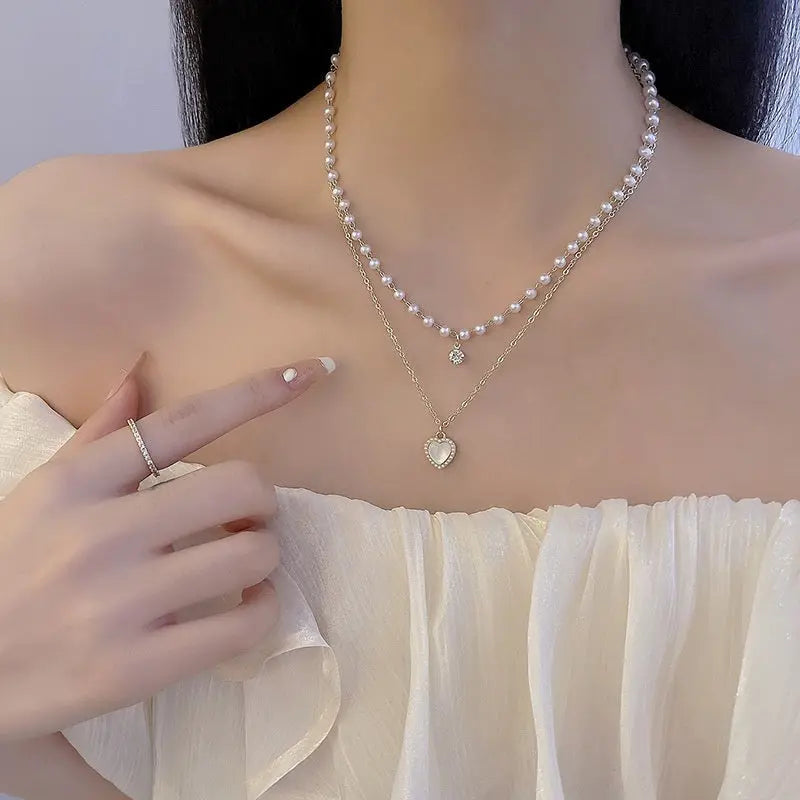 Layered gold-tone pearl choker and a gold link chain with a heart-shaped opal pendant