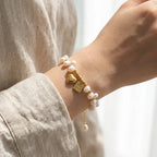 Lifestyle close-up of a woman's wrist wearing the elegant freshwater pearl bracelet with its gold heart charm