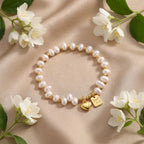 Freshwater pearl bracelet with a gold heart charm elegantly displayed on soft beige silk with jasmine flowers