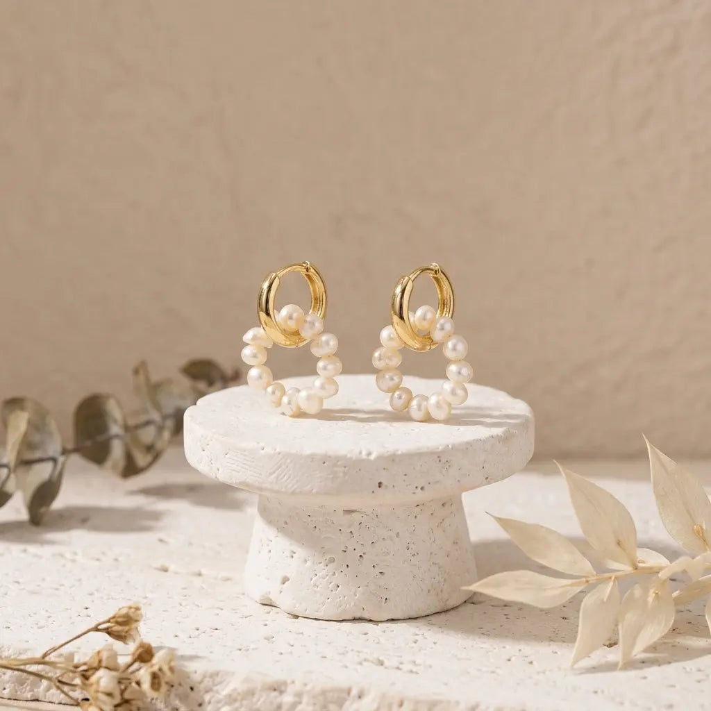 Natural freshwater pearl hoop earrings displayed on a white stone pedestal minimalist lifestyle setup