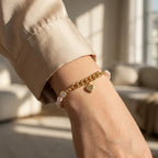 Close-up of a woman's wrist wearing the gold link and freshwater pearl heart charm bracelet