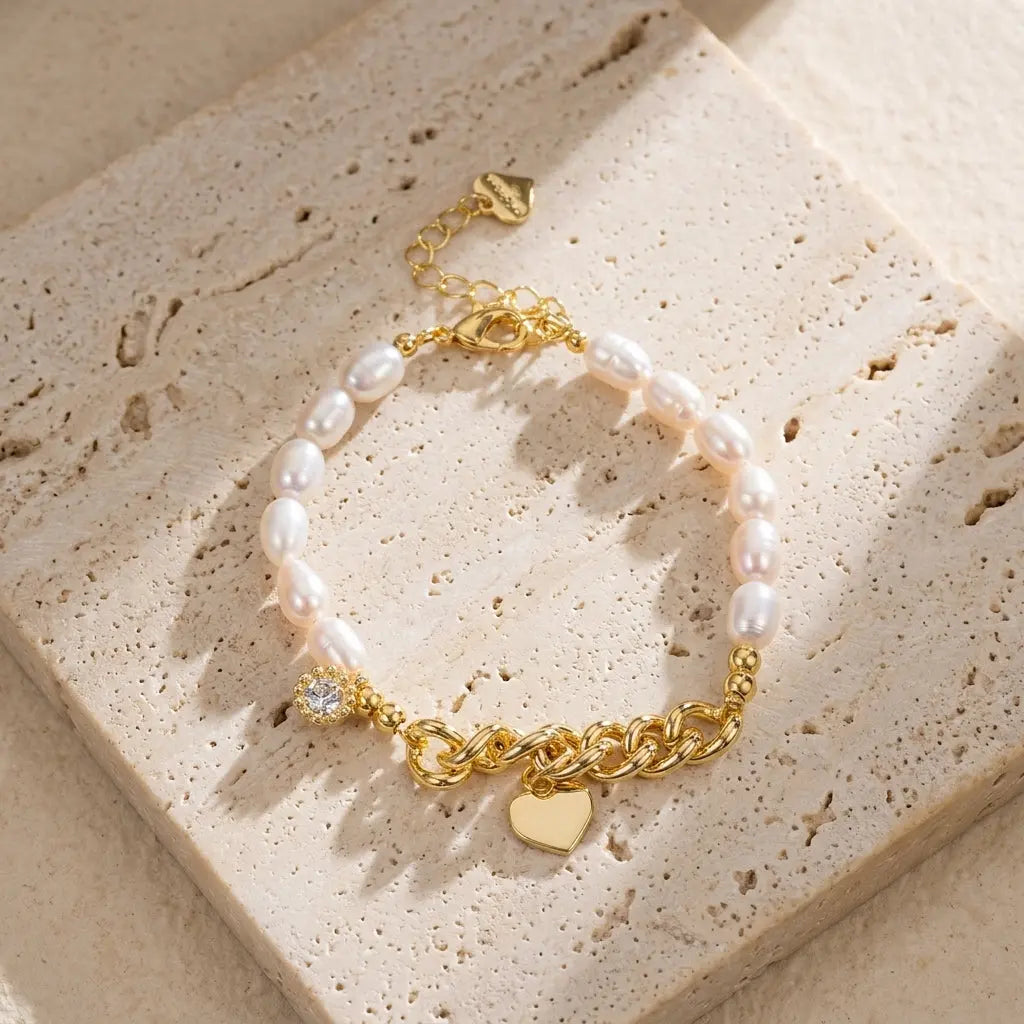 Flat lay of the asymmetrical freshwater pearl and gold chain bracelet on a travertine stone surface