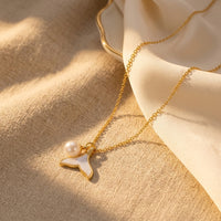 Gold Fishtail Pearl Pendant Necklace in a warm, elegant golden hour lifestyle setting with soft linen drapery