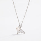 Silver Fishtail Pearl Pendant Necklace on a white pearlescent shell plate, bright elegant morning light aesthetic