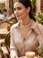 Model wearing Gold Layered Pearl Choker and Coin Pendant Necklace Set in elegant outdoor lifestyle setting