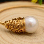 Detailed macro close-up of the artisanal hand-wrapped gold-toned wire and lustrous freshwater pearl details