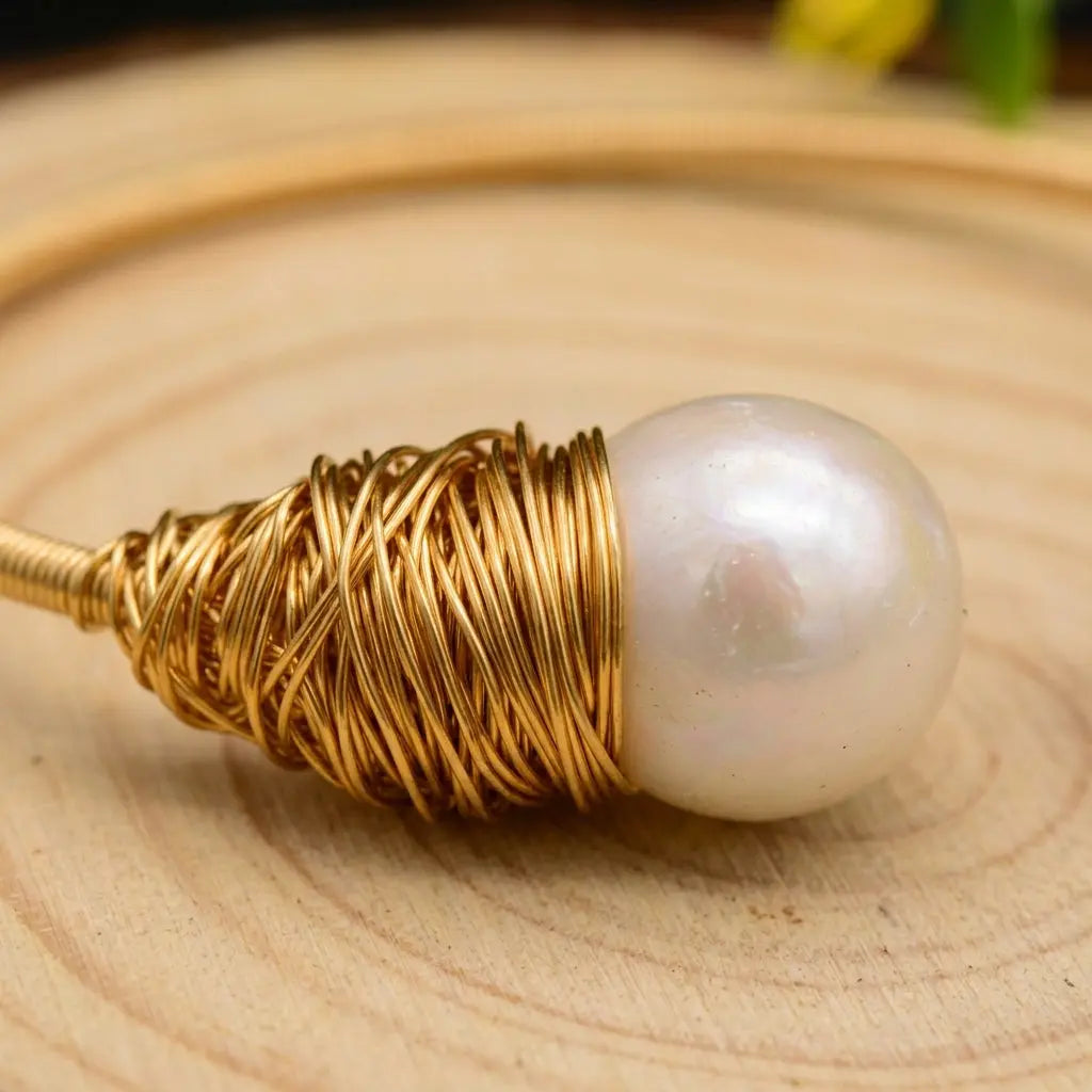 Detailed macro close-up of the artisanal hand-wrapped gold-toned wire and lustrous freshwater pearl details